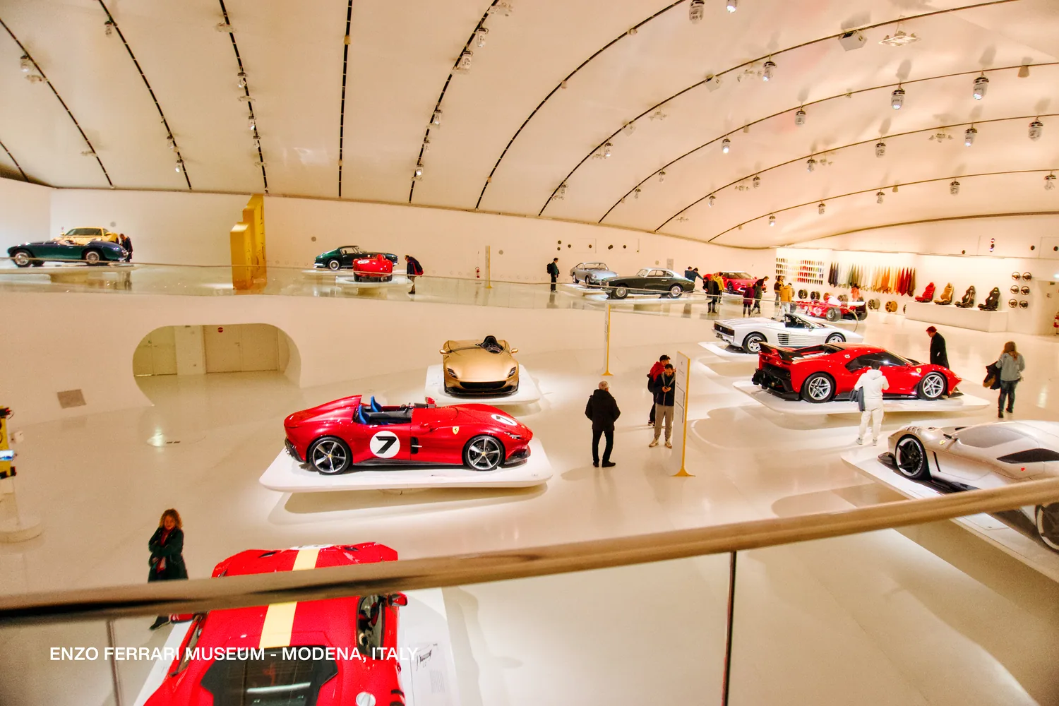 Sala del Museo Enzo Ferrari con autos en plataformas blancas